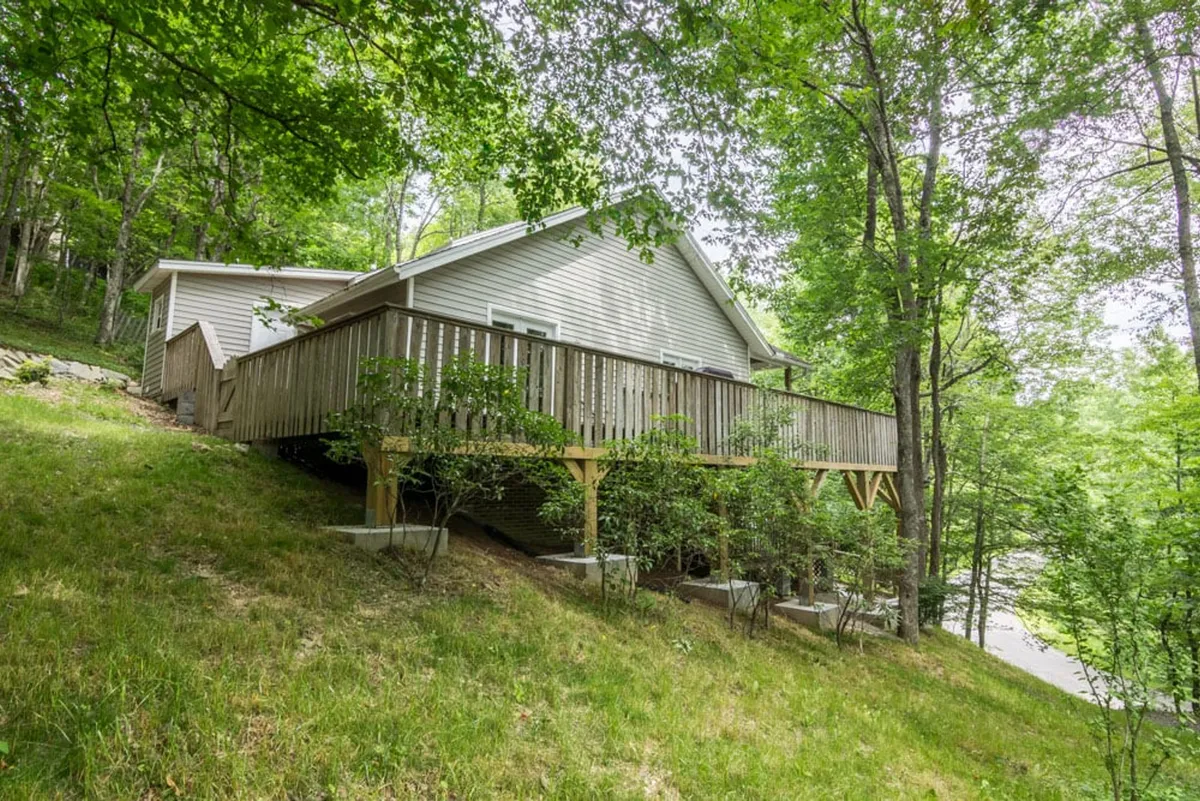A wide view of the wooden deck with sturdy railings, seamlessly blending the home's structure with the surrounding forest. The scene highlights a tranquil outdoor space ideal for watching sunsets, gathering for conversation, or preparing for a day of local adventure.